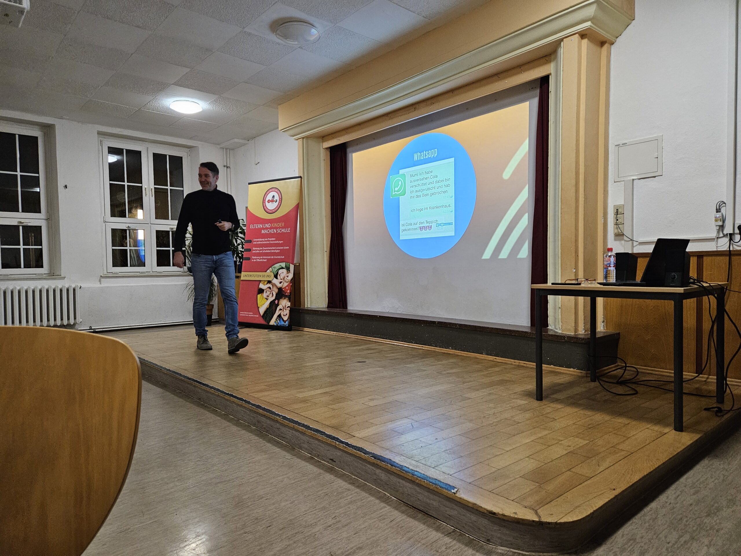 Vortrag über WhatsApp und Medienkompetenz auf einer Schulbühne, Referent spricht vor Eltern oder Lehrkräften.