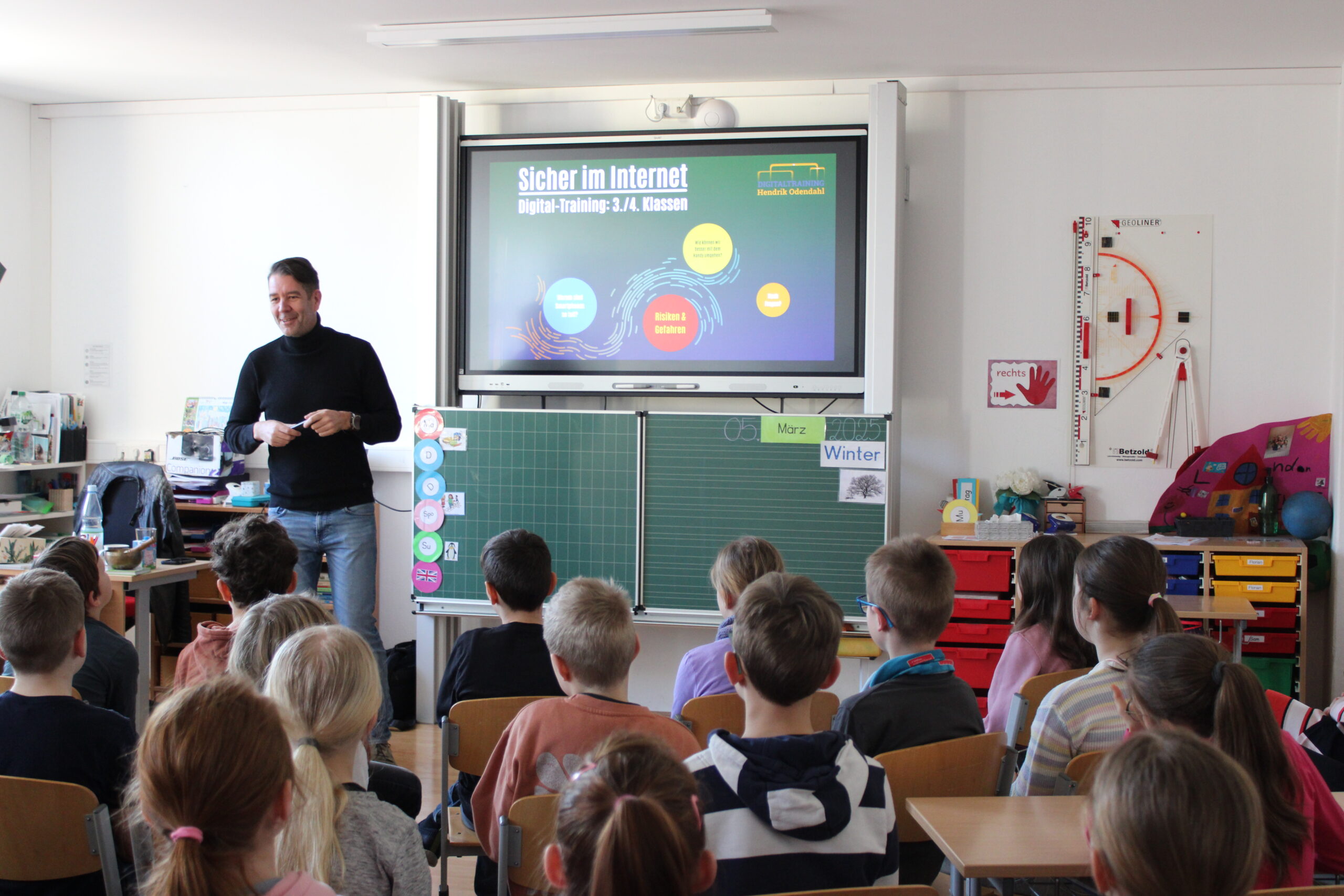 Grundschüler:innen beim Medienkompetenztraining „Sicher im Internet“ mit einem Referenten im Klassenzimmer.